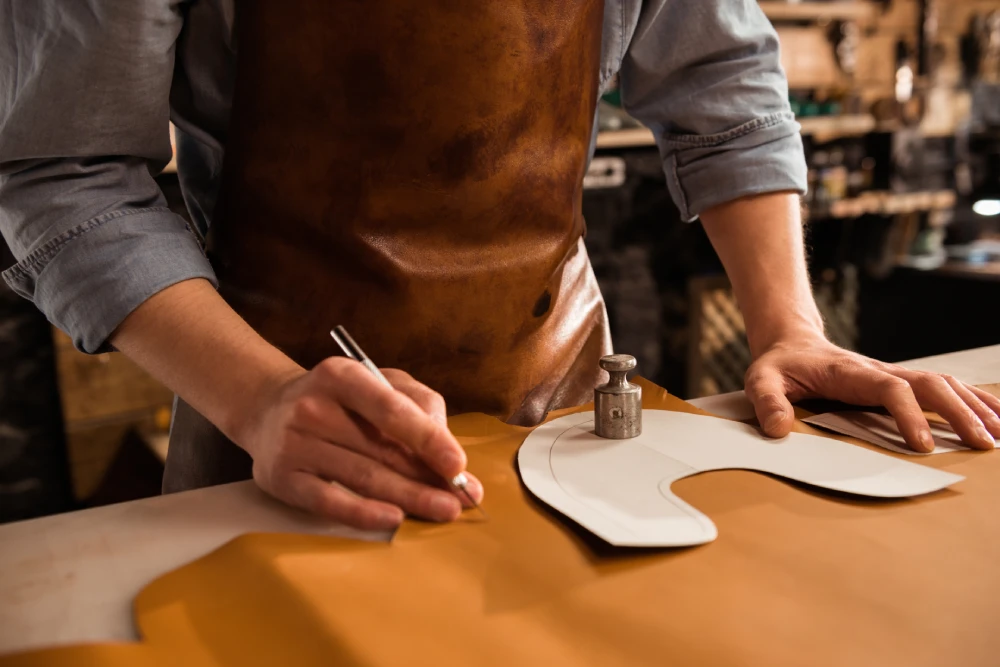 Close up male shoemaker cutting leather textile